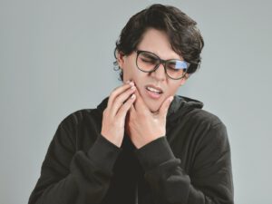 Man met handen bij kaak, herkenning van TMJ klachten