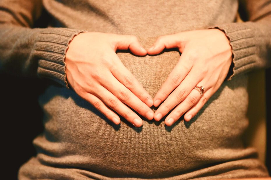 Zwangere vrouw vormt met haar handen een hartje op haar buik